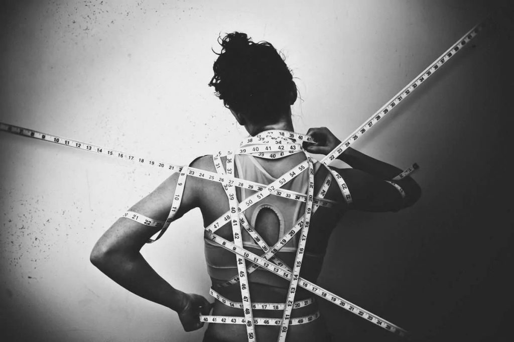 woman wrapped in body measuring tapes